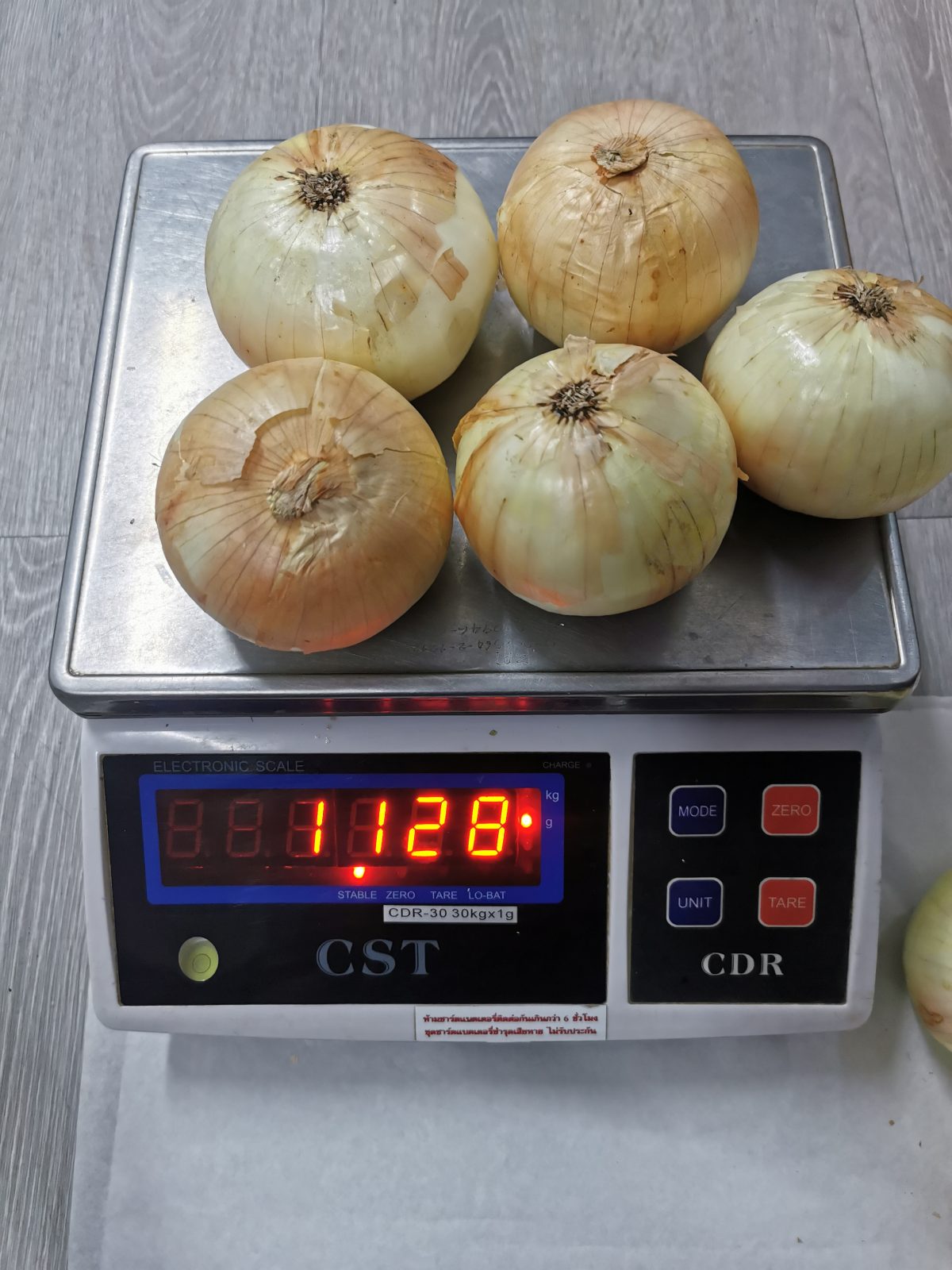 หอมหัวใหญ่บนเครื่องชั่ง แสดงน้ำหนัก 1.128 กิโลกรัม